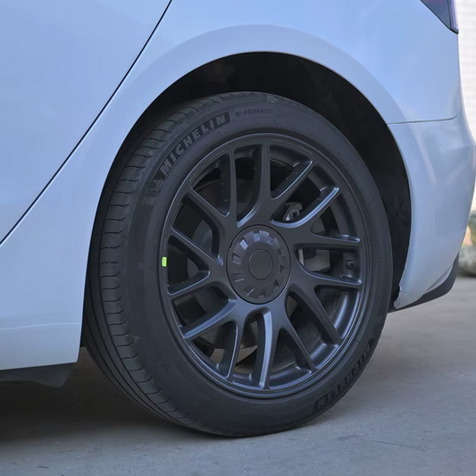 Detailansicht der sportlichen grauen Nabenkappe auf der dunklen Felge eines Tesla Model 3 Highland (2024).