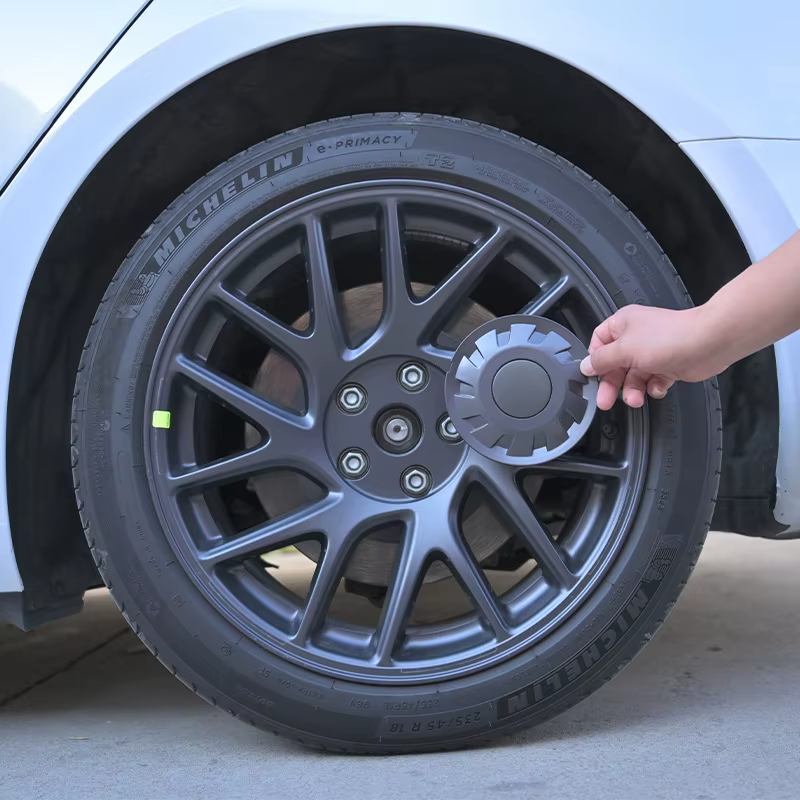 Installation: Hand montiert graue Nabendeckel auf die Felge des Tesla Model 3 Highland 2024.